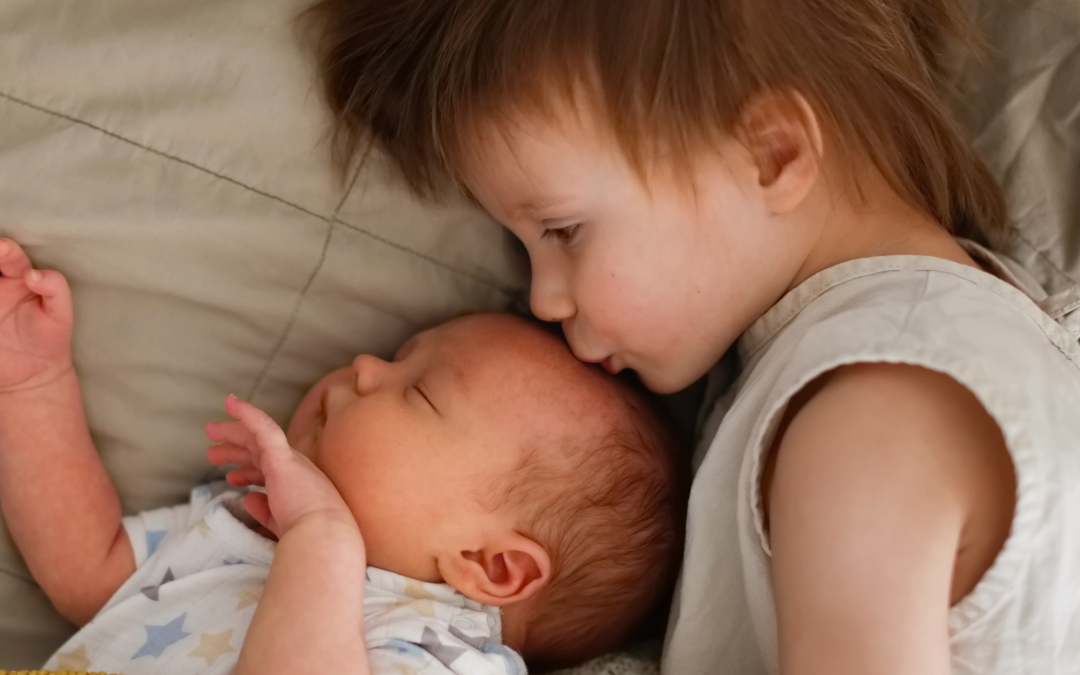 a little boy kissing his baby brother